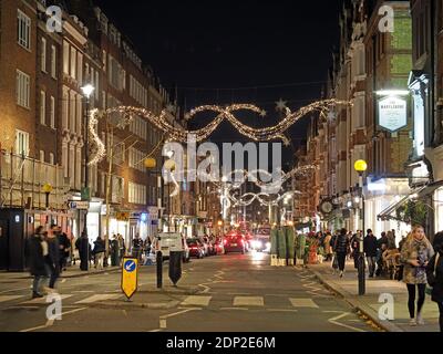 View looking up at the festive Christmas decorations at night in Marylebone High Street London 2020 Stock Photo
