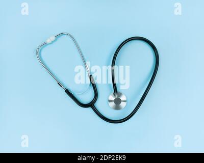 Black stethoscope on soft blue background. Simple flat lay. Stock Photo