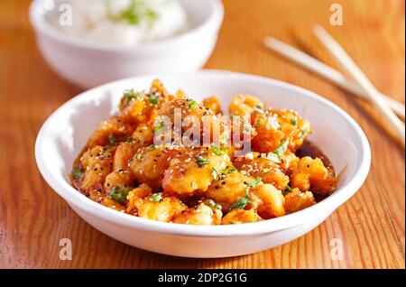 Asian honey glazed sesame chicken in a soy based sauce topped with sesame seed served with white rice Stock Photo