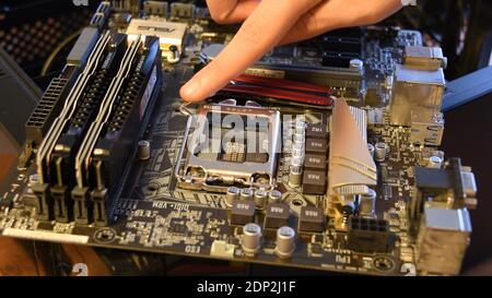 Closeup of modern PC motherboard hardware with empty space for CPU. Male finger touches fixer for CPU. Computer hardware technology background. Odessa Stock Photo