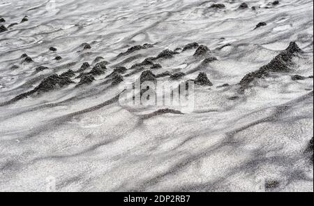 Abstract dirty black sand waves on snow texture. Stock Photo