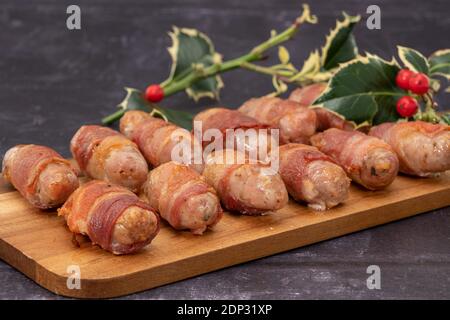 Pigs in blankets or sausages wrapped in bacon on a wooden board Stock Photo
