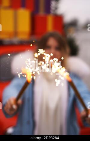 Female hands are holding burning sparklers. Woman outdoors in winter Stock Photo