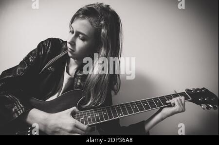 Girl playing on the semi-acoustic guitar at home party. Stock Photo