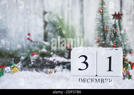 New Years Eve. White wood calendar blocks with the date December 31st and Christmas decorations with snow. Selective focus with blurred background. Stock Photo