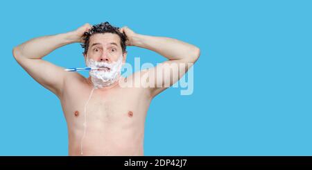 white man holding a toothbrush, washing his head, looks directly and late Stock Photo