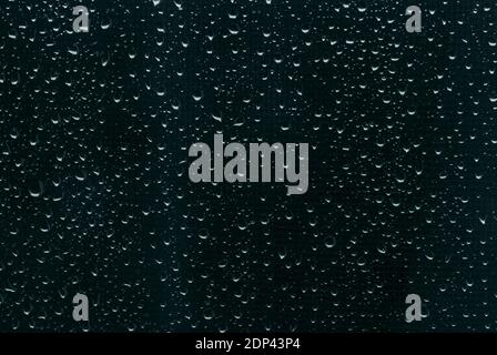 Raindrops on dark blue-green window glass as background Stock Photo