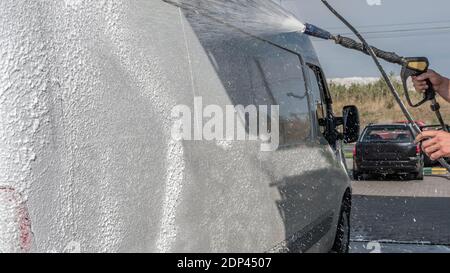Car wash, car wash worker washes the truck, the man foams the car, washes away the dirt Stock Photo