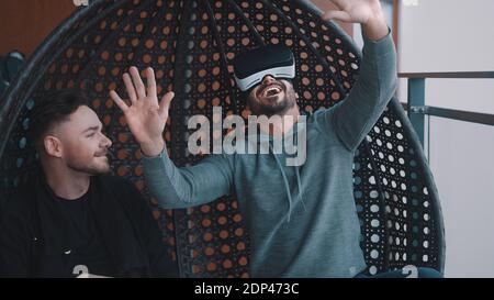 Amused gay couple testing the virtual reality glasses at home. High quality photo Stock Photo