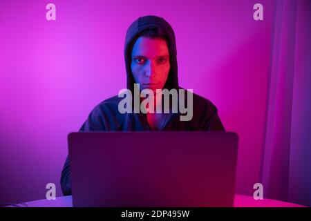 Gamer plays on a laptop. The programmer writes the code. Man on a colored background Stock Photo