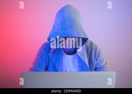Gamer plays on a laptop. The programmer writes the code. Man on a colored background Stock Photo