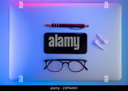 On a colored background, Laptop, glasses, pen, headphones, top view. Business concept Stock Photo
