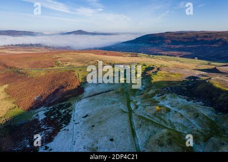 Aerial view looking down through fog on a frosty, frozen rural landscape (Wales, UK)