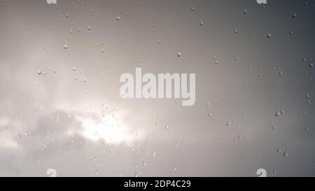 Drops of water on glass against the sky.Beautiful raindrops on glass, macro drops flow down the window. Stock Photo