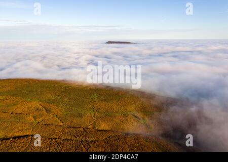 Aerial view of mountains rising through a sea of clouds (Skirrid Fawr, Wales, UK).