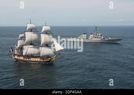 The Arleigh Burke-class guided-missile destroyer USS Mitscher (DDG 57), right, provides a warm welcome to the French tall ship replica the Hermione in the vicinity of the Battle of Virginia Capes off the east coast of USA on June 2, 2015 The original the Hermione brought French Gen. Marquis de Lafayette to America in 1780 to inform Gen. Washington of France?s alliance and impending support of the American Revolutionary War. The symbolic return of the Hermione will pay homage to Lafayette and the Franco-American alliance that brought victory at the Battle of Yorktown in 1781. The Hermione will Stock Photo