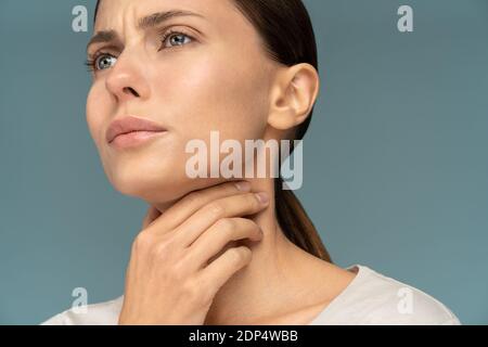 Closeup of sick woman having sore throat, tonsillitis, feeling sick, caught cold, suffering from painful swallowing, strong pain in throat, holding ha Stock Photo