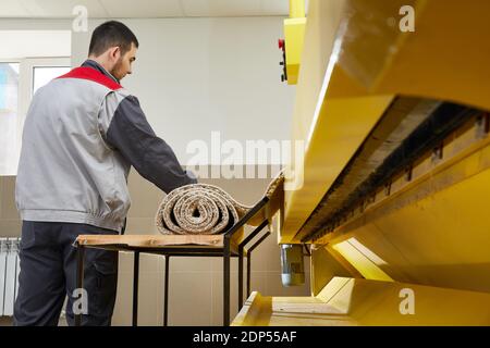 Man operating carpet automatic washing machine in professional laundry service Stock Photo