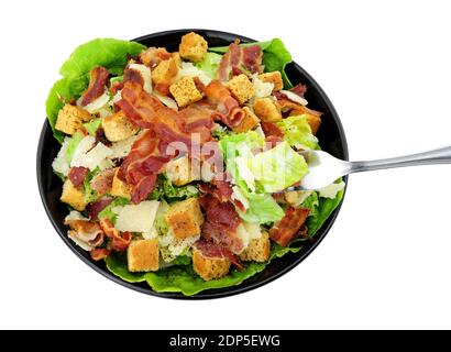 Bacon Caesar salad with romaine lettuce and parmesen cheese shavings served in a black dish isolated on a white background Stock Photo