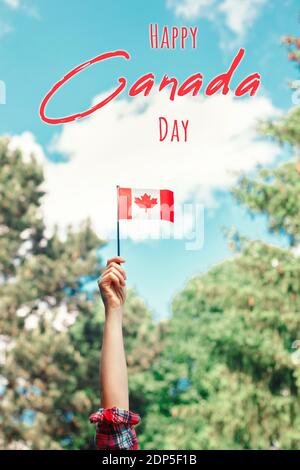Happy Canada Day. Holiday card with text. Human hand arm waving Canadian flag against blue sky. Proud citizen man celebrating national Canada Day on 1 Stock Photo