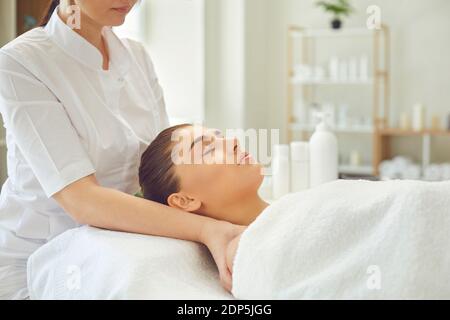 Woman masseur making professional manual relaxing massage for young womans face and shoulders Stock Photo