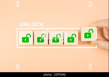 Unlock concept. Hand putting wooden cube block shape with unlock icon sign on progress bar. OPEN new business opportunities Stock Photo