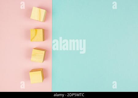 four wooden cubes on pink background. Creative flat lay with copy space. Mockup for design. Stock Photo