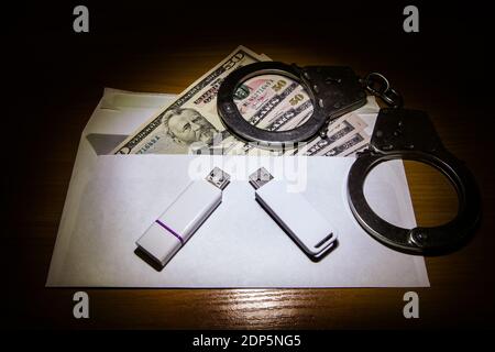 Envelope with an American Dollars Handcuffs and Two USB Drives on the Table closeup Stock Photo