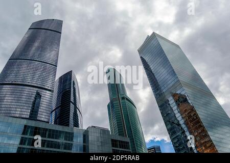Glass modern skyscraper buildings opposite dark cloudy and stormy sky Stock Photo