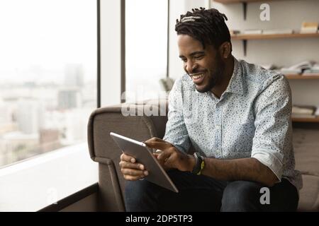 Smiling biracial man use tablet relaxing at home Stock Photo