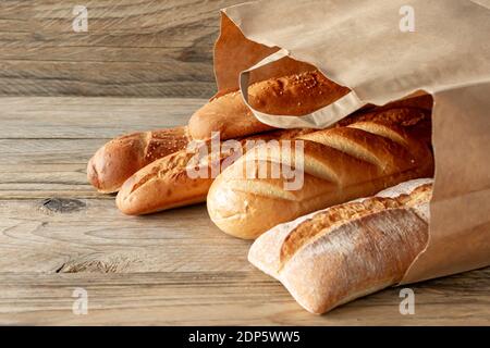 arranged assorted baking products in paper bag on rustic wooden tabletop. Stock Photo