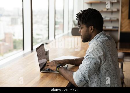 Millennial biracial man work online on computer at home Stock Photo
