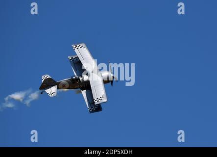 Pitts Model 12  stunt byplane  with smoke trail and blue sky. Stock Photo
