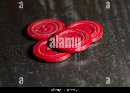 Red plastic sewing buttons isolated on dark background. Stacked round sewing buttons. Stock Photo
