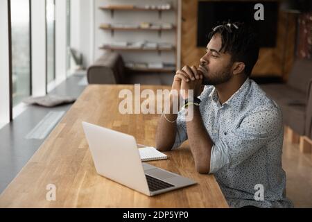 Pensive biracial man work on laptop thinking Stock Photo