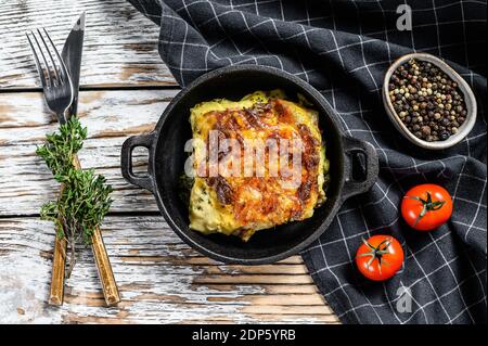 Spinach lasagna in a pan, vegetarian food. White wooden background. Top view. Stock Photo