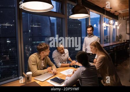 Diverse colleagues work in office late at night Stock Photo