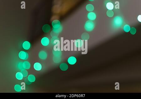 Abstract green bokeh background of blurred lights garlands on dark gray background, for Christmas, New Year and holidays Stock Photo