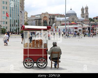 ISTANBUL,TURKEY-JUNE 7:Man selling Turkish Bagel Simit and cold waters  on Simit cart at Taksim Square.June 7,2015 in Istanbul,Turkey. Stock Photo