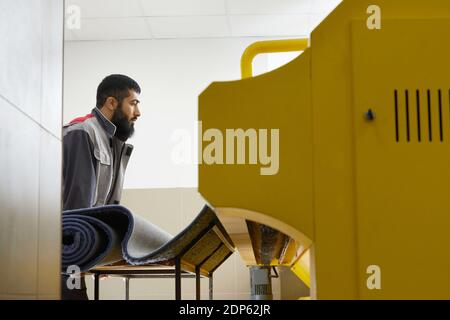 Man operating carpet automatic washing machine in professional laundry service Stock Photo
