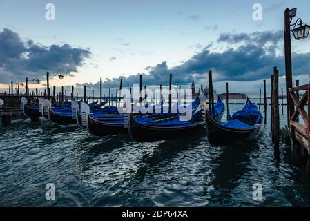 A row of moored gondole at the Traghetto Gondola Molo jetty with views ...