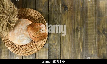 Two round loaves of bread and ears of wheat top view as background Stock Photo