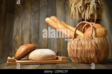 Still life with fresh various breads in a wicker basket on a wooden background Stock Photo