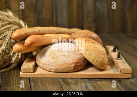 Different breads on cutting board on a wooden background Stock Photo