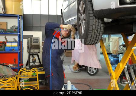 A concentrated European mechanic working on a car tire in a garage Stock Photo