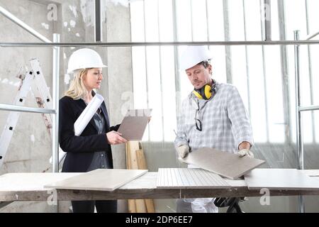 man and woman architect interior designer and foreman worker together with tiles samples and decorative materials discussing the project for interior Stock Photo