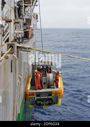 The Crew of a Seismic Vessel in the South Atlantic getting lowered into the water alongside the Vessel to begin a Workboat mission at Sea. Stock Photo