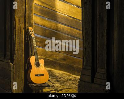 Acoustic electric guitar leaning against a chair in the mist of the night Stock Photo