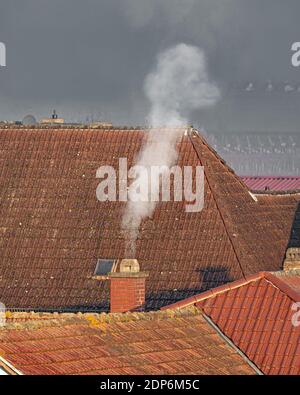 Roofs of an old village with a smoking chimney and copyspace Stock Photo