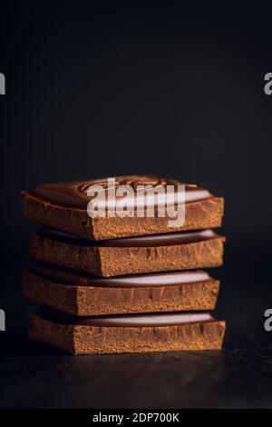 Pieces of chocolate bars on the black rustic background. Selective focus. Shallow depth of field. Stock Photo